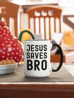 a white coffee mug sitting on top of a table next to a bowl of cookies