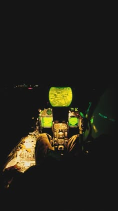 the cockpit of an airplane at night with its lights on and two people sitting in it