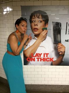 two women standing in front of a subway poster with the words lay it on thick