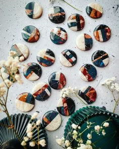 many different types of buttons on a white surface next to flowers and a vase with dried flowers in it