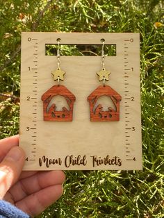 a pair of wooden earrings with an image of a dog in a house on it