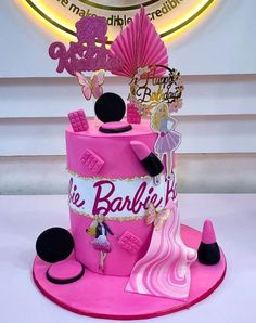 a pink cake decorated with barbie dolls and accessories