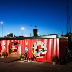 a red shipping container sitting on top of a parking lot next to a tall building