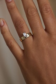 a woman's hand with a gold ring on it and a diamond in the middle