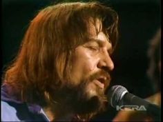 a man with long hair is singing into a microphone