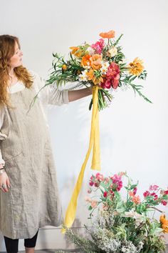 a woman holding a bouquet of flowers in front of a white wall with the words lovemyress on it