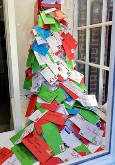 a christmas tree made out of post it notes is shown in front of a window