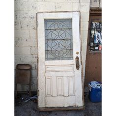 an old white door with stained glass on it and a trash can in the background