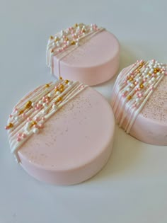 three pink and gold decorated soaps on a white surface