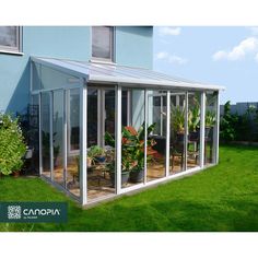 a house with glass walls and plants in the yard