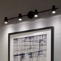 an abstract painting hangs on the wall next to two light fixtures and a framed photograph