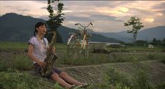 a young boy sitting on the ground playing a saxophone