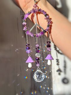 a woman's hand holding a purple and white beaded bracelet with charms on it