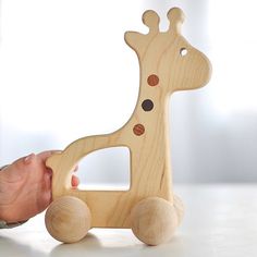 a wooden giraffe toy being held by someone's hand