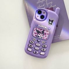 a purple cell phone sitting on top of a table next to a book and pen