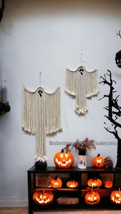 halloween decorations with pumpkins on display in front of a white wall and black tree