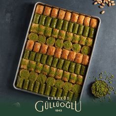 a pan filled with green food next to nuts and other ingredients on a table top