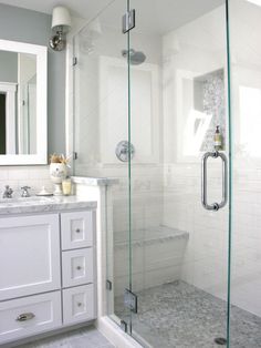 a bathroom with a walk in shower next to a white sink and mirror on the wall