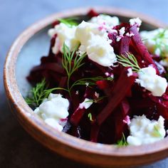 a wooden bowl filled with beets and feta cheese on top of a table