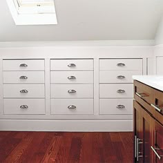 an empty kitchen with white cabinets and wood flooring on the walls, along with a skylight