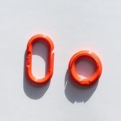 two orange plastic objects sitting on top of a white surface with the letters o written in it