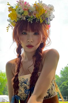 a woman with long red hair wearing a flower crown on her head and holding a knife in one hand