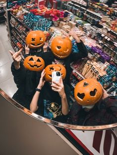 three people holding pumpkins in front of their faces and taking a selfie at the store