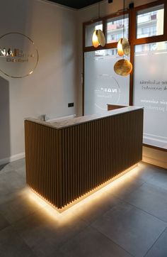 an illuminated reception table in front of a window with two hanging lights on the wall