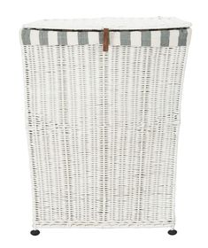 white wicker laundry hamper with leather handles and brown straps on the bottom, sitting against a white background