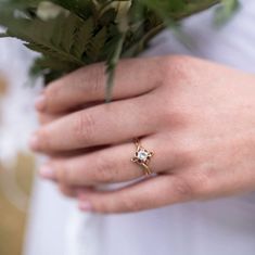 a close up of a person's hand holding a bouquet of flowers and a ring