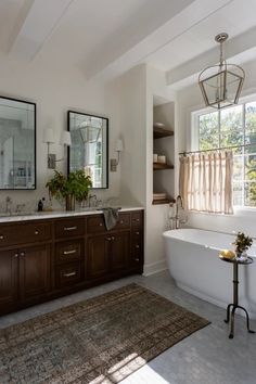 a bath room with a tub a mirror and a rug on the floor in front of it