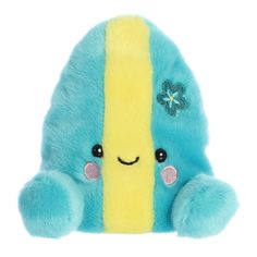 a blue and yellow stuffed animal sitting on top of a white surface next to a flower