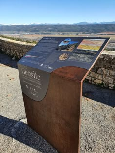 a wooden box sitting on the side of a road next to a stone wall and mountains