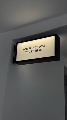 a sign hanging from the side of a wall that says you're not lost, you're here