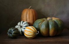 three pumpkins and two gourds on a table