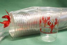 two plastic cups with red lobsters on them are sitting next to each other and wrapped in plastic