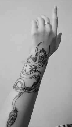 a hand with a dragon tattoo on it's arm and the other hand holding an object in the air