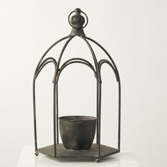 a black pot sitting inside of a metal cage on top of a white tablecloth