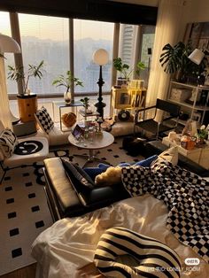 a living room filled with lots of furniture and windows overlooking the cityscape in the distance