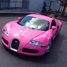 a pink bugatti is parked on the street in front of a building with windows