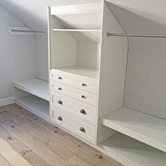 a white closet with drawers and shelves in an attic space that also has wood flooring