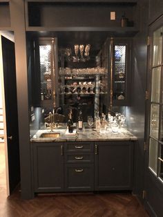 a bar with lots of bottles and glasses on it's counter top in a kitchen