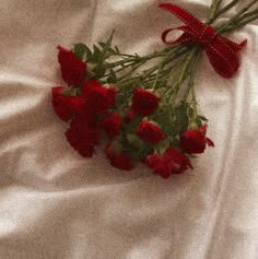 some red flowers are laying on a white sheet