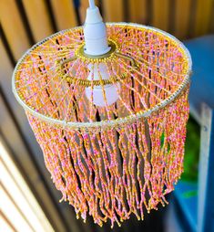 a pink and yellow chandelier hanging from a wooden ceiling with beads on it