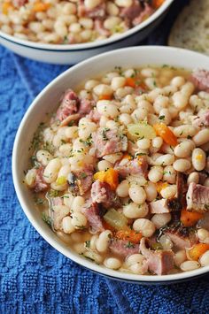 two white bowls filled with ham and bean soup on top of a blue table cloth