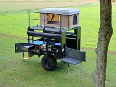 an off - road vehicle is parked in the grass near a tree