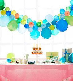 a party table with balloons and cupcakes on it