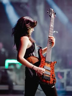 a woman holding a bass guitar on stage