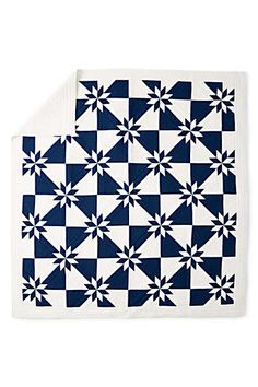 a blue and white quilt on top of a table with a black and white checkerboard pattern