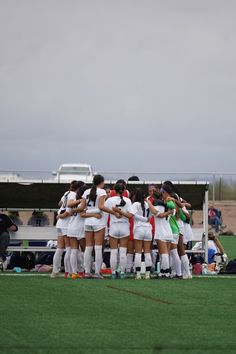 a group of women's soccer players huddle together on the field